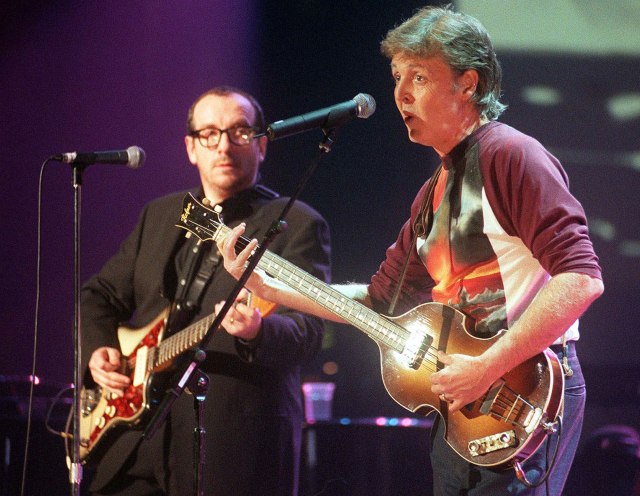 Musicians Elvis Costello and Paul McCartney perform together. (AP Photo/Sean Dempsey, linked from People.com)